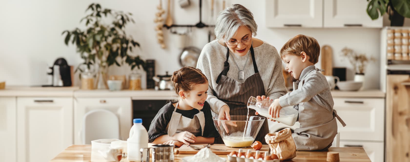 An elderly person and two children baking in a cozy kitchen.