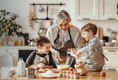 An elderly person and two children baking in a cozy kitchen.